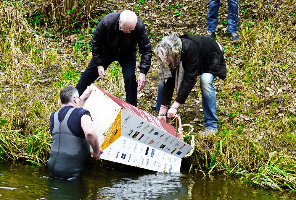 : Holger Mahlke (in der Trave stehend), Rolf Witthöft (links) und Michael Gilbert (rechts) eine Blumentasche aus der Trave. Foto: Prodibra/hfr